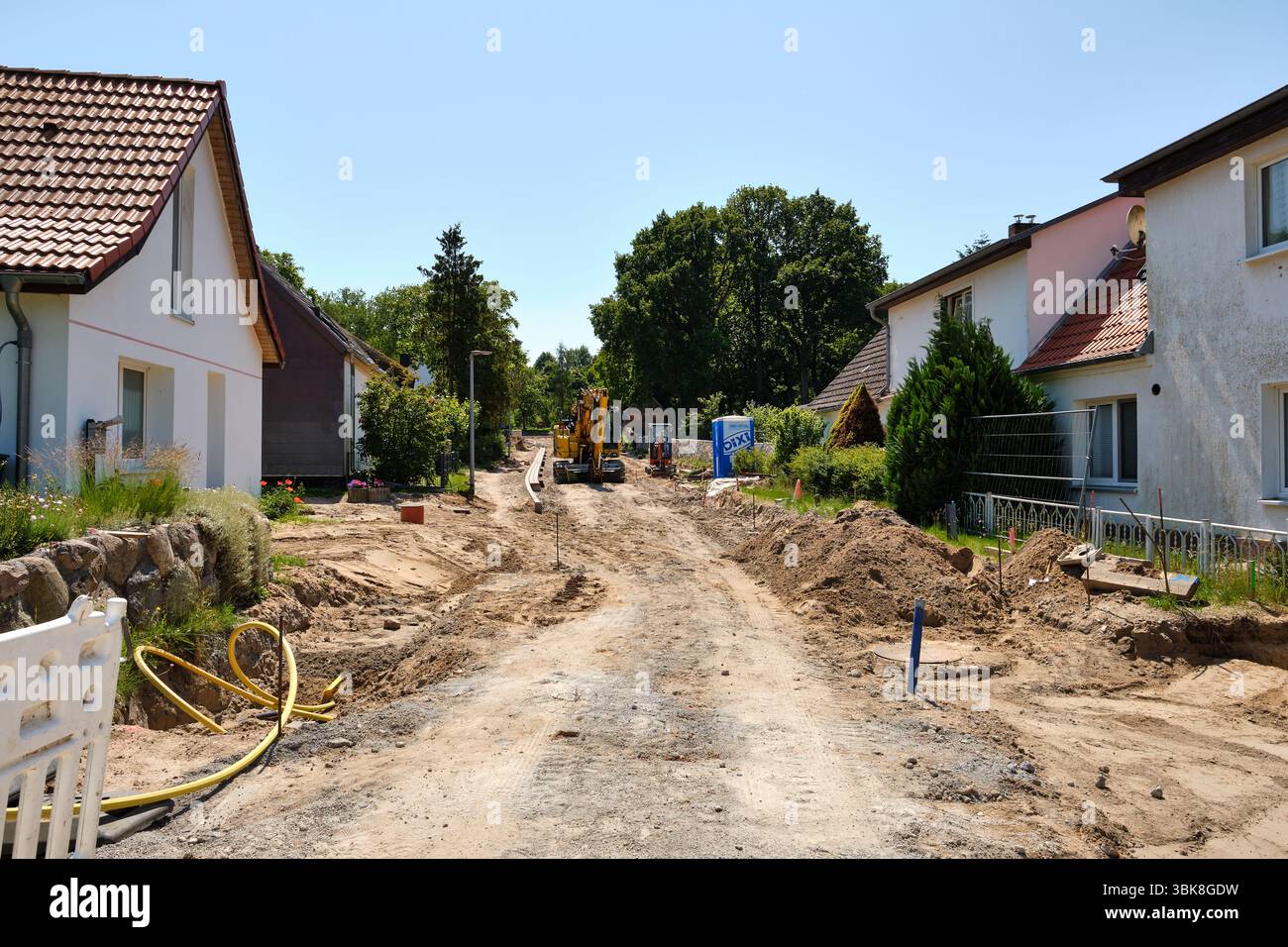 14. Juni 2025 - Benz-Deutschland: Bagger und Toilette parken während der Wochenendferien auf einer ausgegrabenen Wohnstraße, mit Baumaschinen und Materi Stockfoto