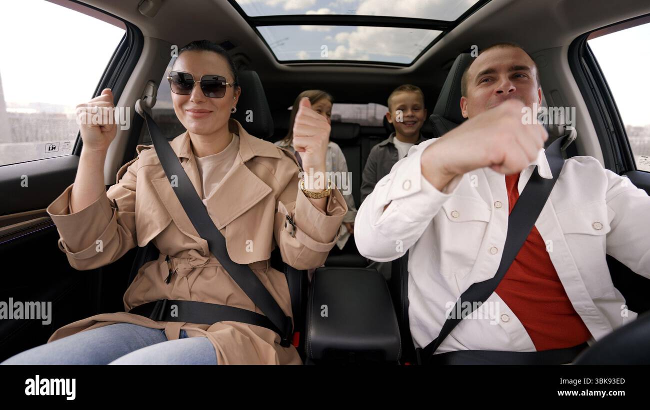 Familienmitglieder tanzen, singen und genießen fröhliche Musik während eines pulsierenden Roadtrips und schaffen gemeinsam freudige Erinnerungen in komfortablem Fahrzeug Stockfoto