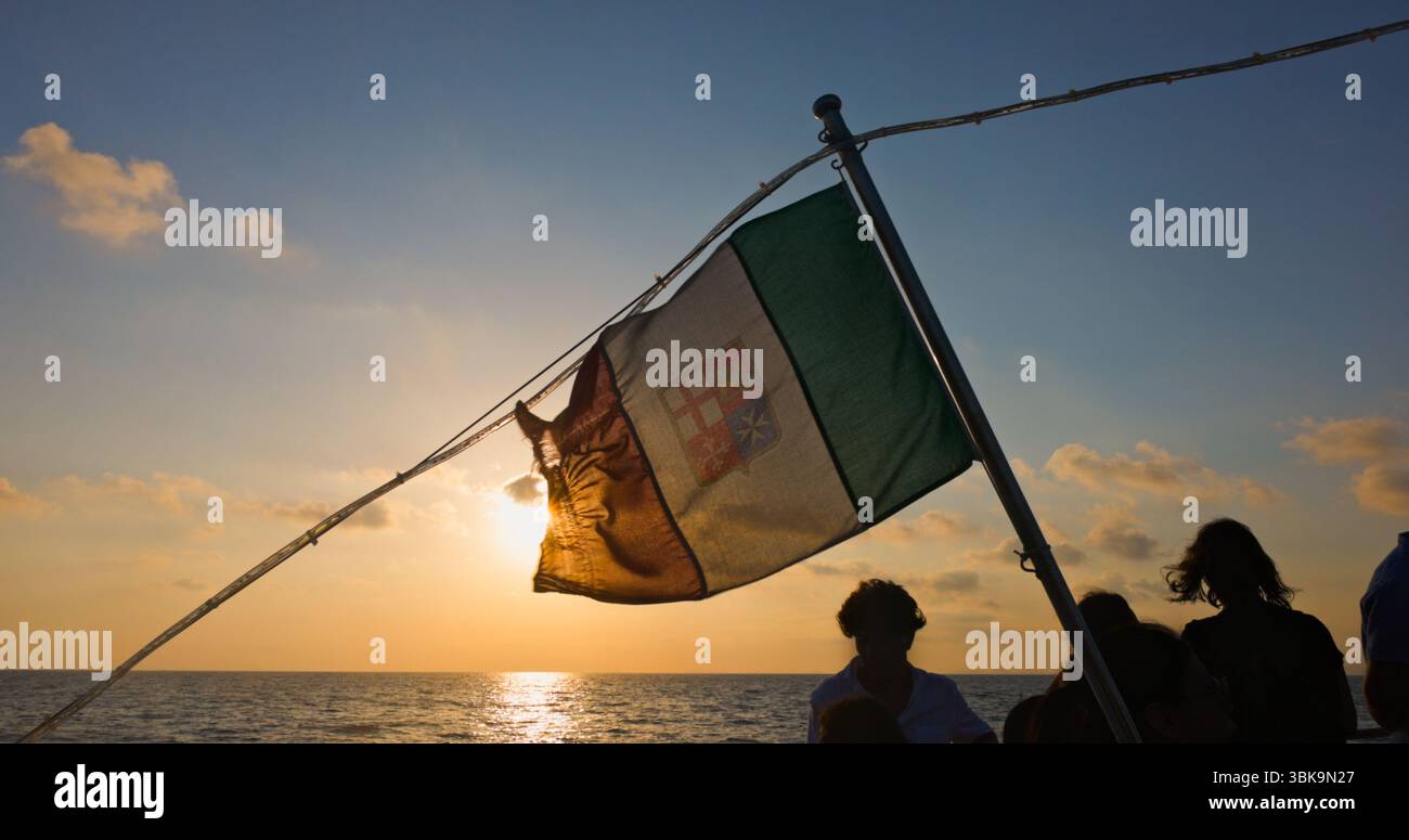 Italienische Flagge mit Sonnenuntergang und Meer im Hintergrund Nahaufnahme Stockfoto