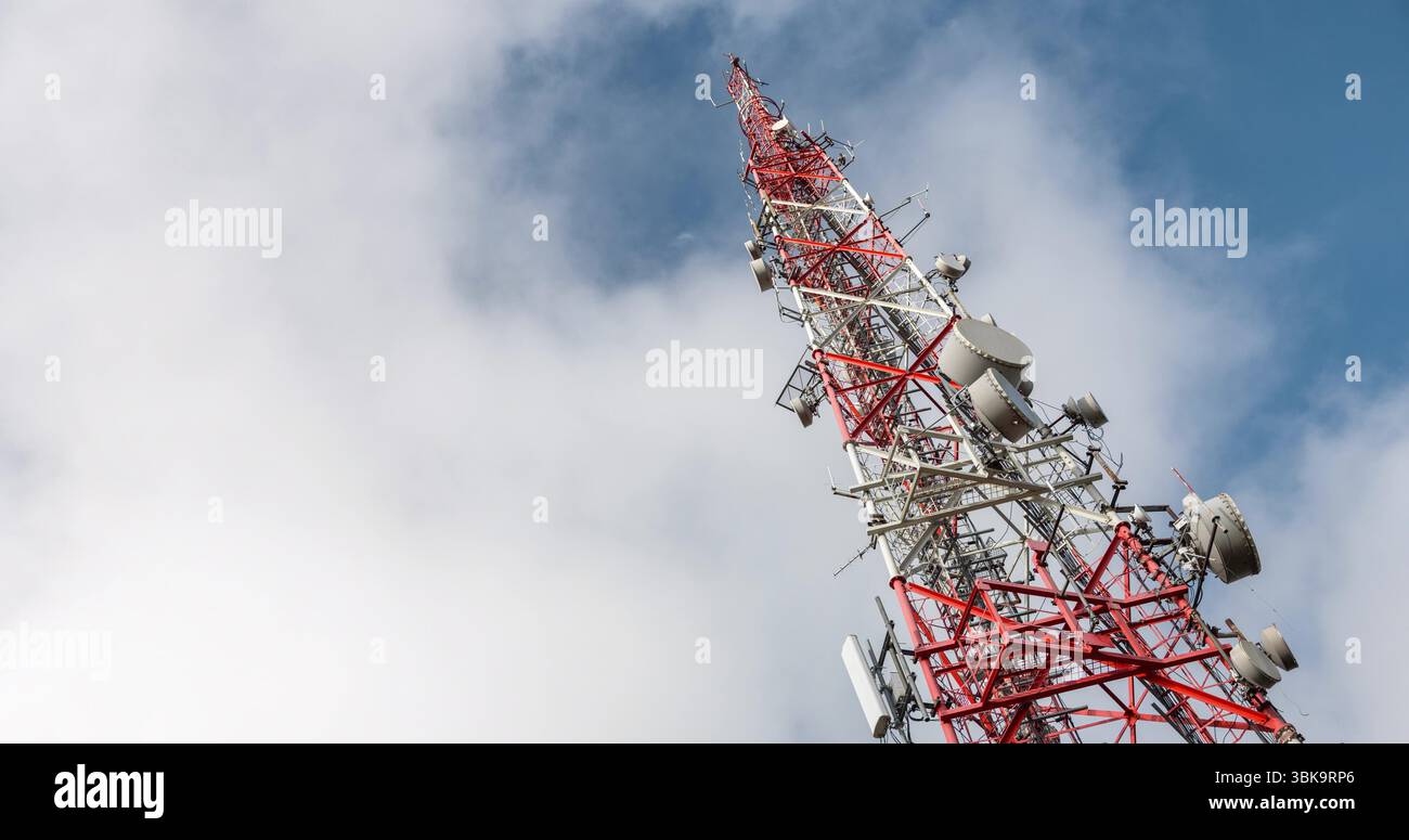 Großer Sendeturm gegen sich schnell bewegende Wolken und blauen Himmel Stockfoto