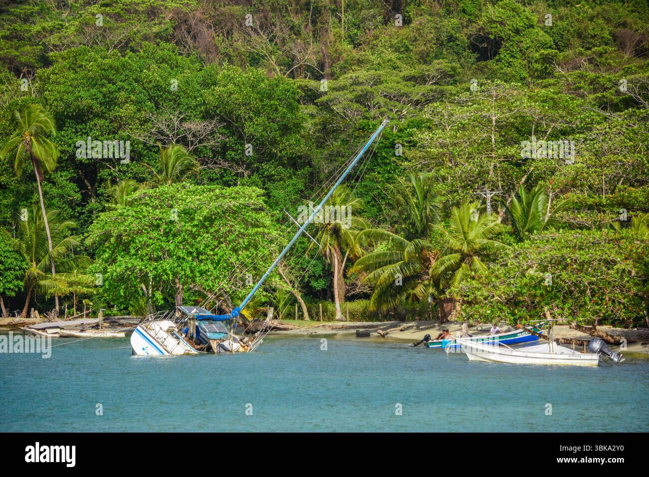 Ein verlassenes Boot ruht in der Nähe der Küste von Sapzurro, Choco, umgeben von üppiger grüner Vegetation und ruhigem Wasser. Stockfoto