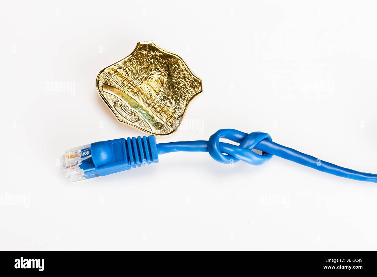 Ein blaues Ethernet-Kabel, das in einem Knoten mit einem Polizeiausweis verbunden ist, liegt auf einem weißen Studiohintergrund und symbolisiert Netzwerkprobleme, Cybersicherheitsprobleme und Stockfoto