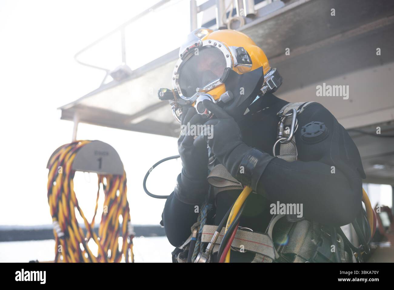 Kommerzieller Taucher, der in der Nähe des Schutzhelms ins Wasser steigt Stockfoto