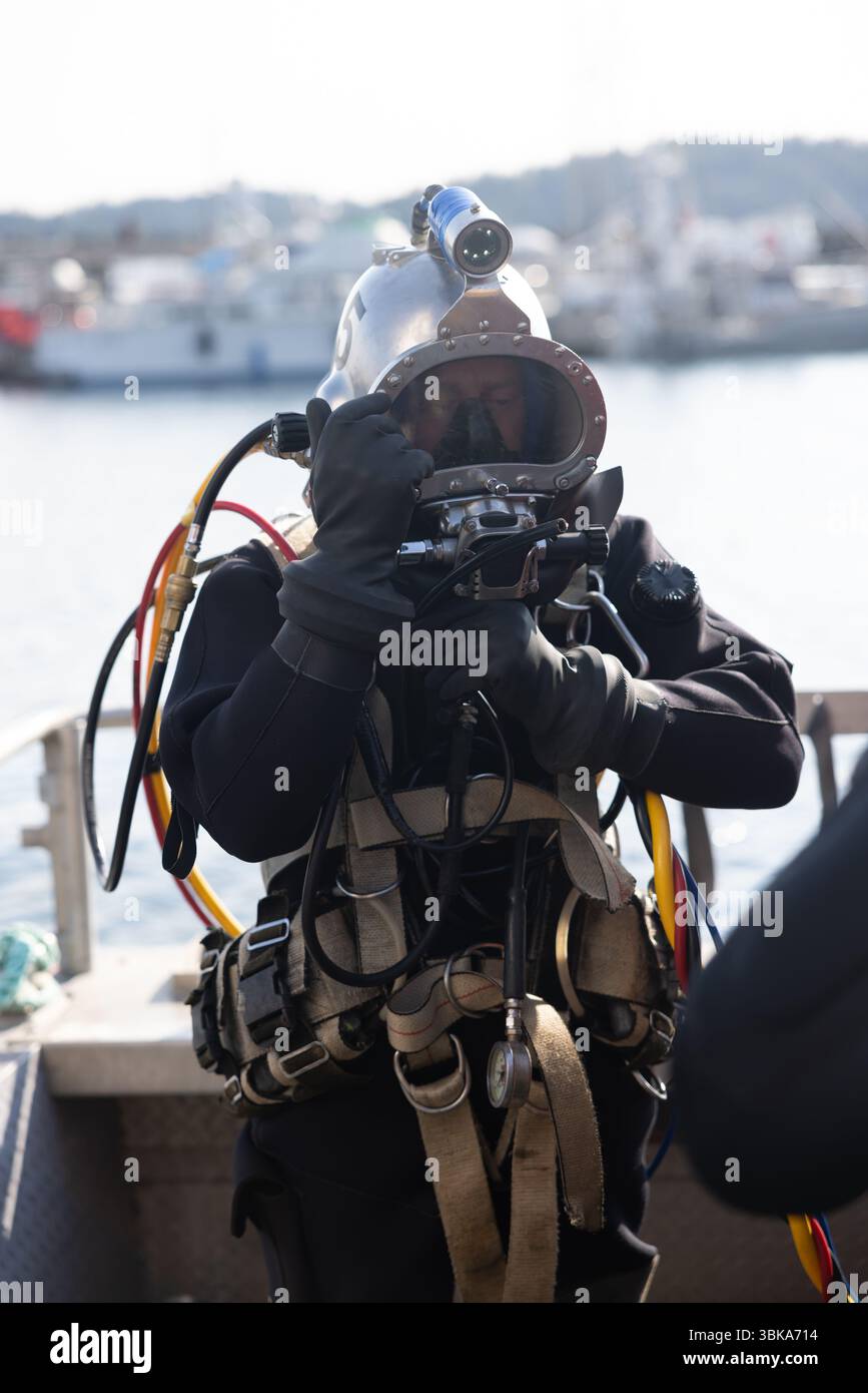 Kommerzieller Taucher, der in der Nähe des Schutzhelms ins Wasser steigt Stockfoto