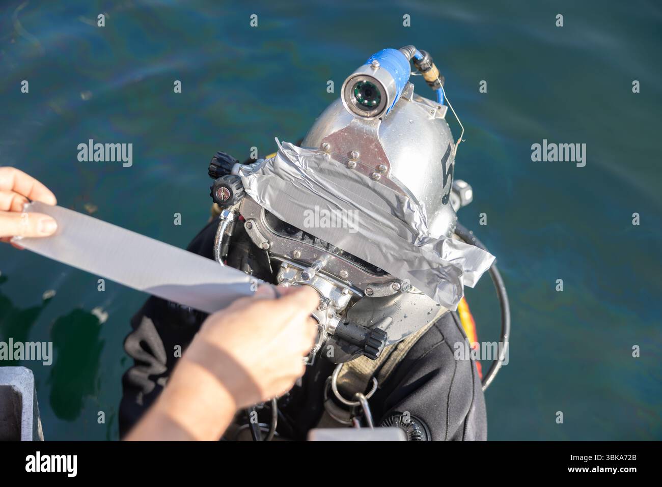 Kommerzieller Taucher, der in der Nähe des Schutzhelms ins Wasser steigt Stockfoto