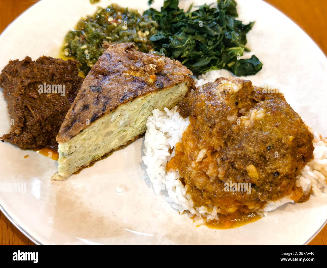 Ein Teller mit traditionellem indonesischem Essen, Nasi Padang, mit Rinderrendang, Ei-Marttabak, grünem Sambal, Maniokblätter und gedünsteter weißer Reis Stockfoto