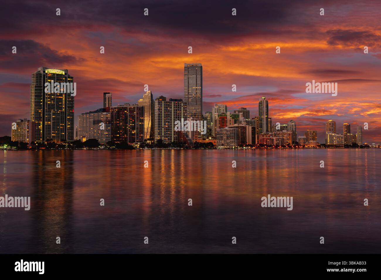 Dieser Blick auf die Skyline von Miami in der Abenddämmerung zeigt die leuchtenden Hochhäuser von Downtown und Brickell, die sich auf dem ruhigen Wasser der Biscayne Bay spiegeln. Stockfoto