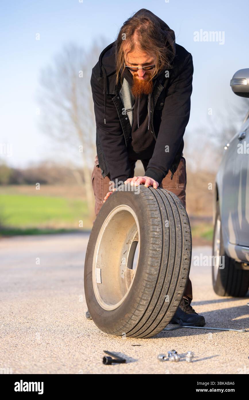 Ein Mann hält Reserverad an der Nähe des Pitstop Stockfoto