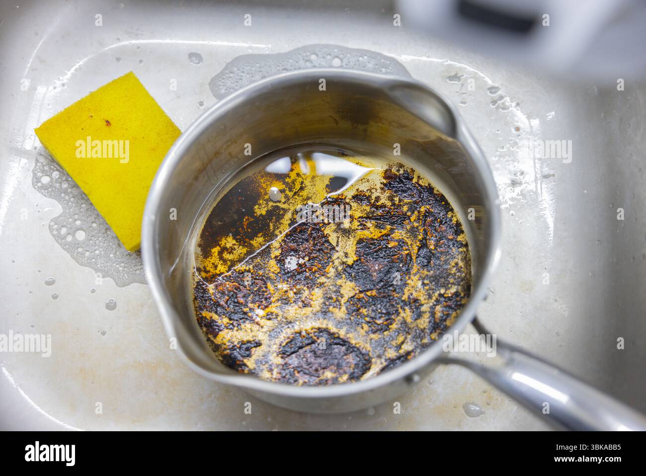 Verbrannter Topf im Waschbecken mit schwarzem Saibling Nahaufnahme Stockfoto