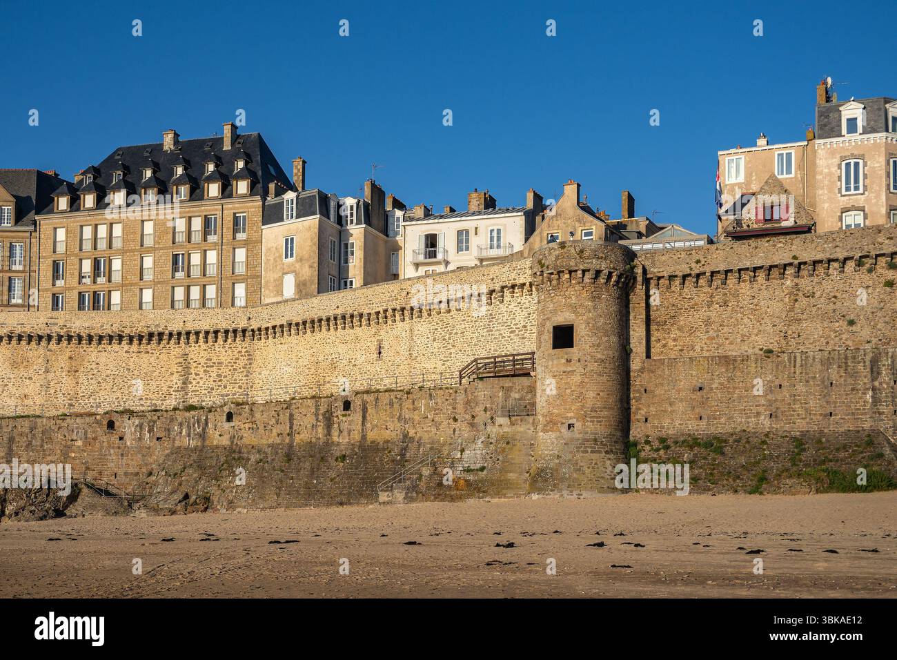 Blick auf den Turm Notre-Dame und die Stadtmauern von Saint-Malo vom Strand bei Ebbe. Historische Granitwälle in warmem Tageslicht, Bretagne, Frankreich Stockfoto