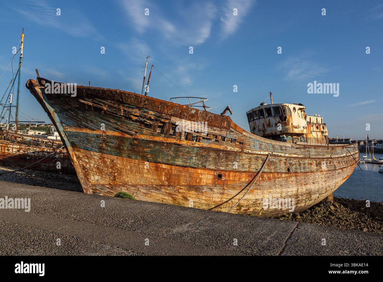 Verwittertes und rostiges Fischerboot Schiffswrack am sillon des Hafens in Camaret-sur-Mer, Bretagne, unter klarem blauem Himmel. Stockfoto