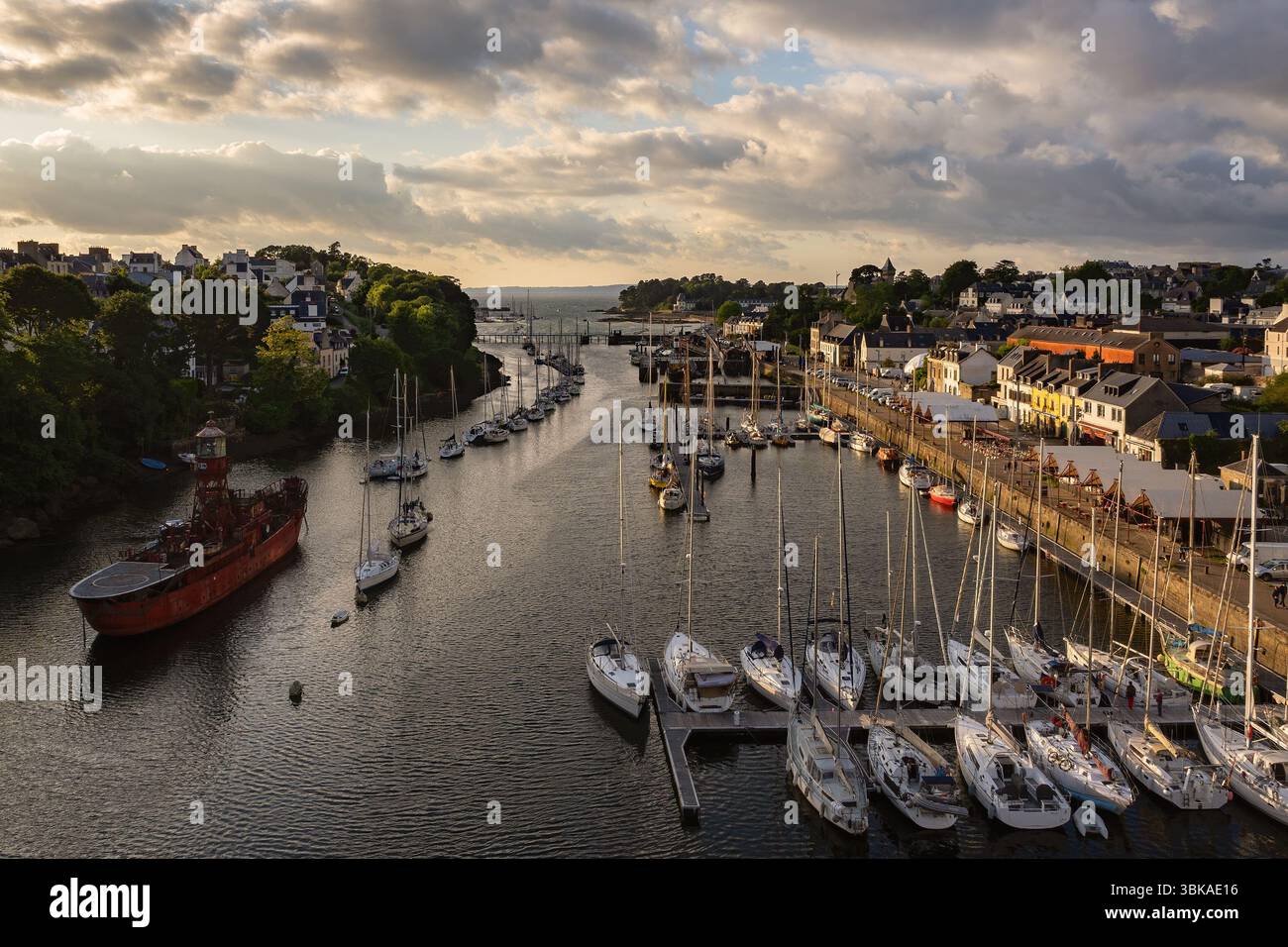 Der goldene Sonnenuntergang beleuchtet den Hafen von Port‑Rhu in Douarnenez, Bretagne, mit verankerten Segelbooten, dem historischen Port‑Musée, üppigem Grün und dramatischem Coloch Stockfoto