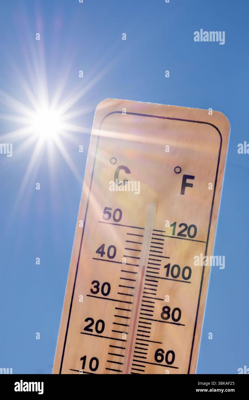 Thermometer, das eine hohe Temperatur mit strahlender Sonne auf einem Hintergrund des blauen Himmels anzeigt. Konzepte für Sommer, heißes Wetter, Hitzewelle usw. Stockfoto