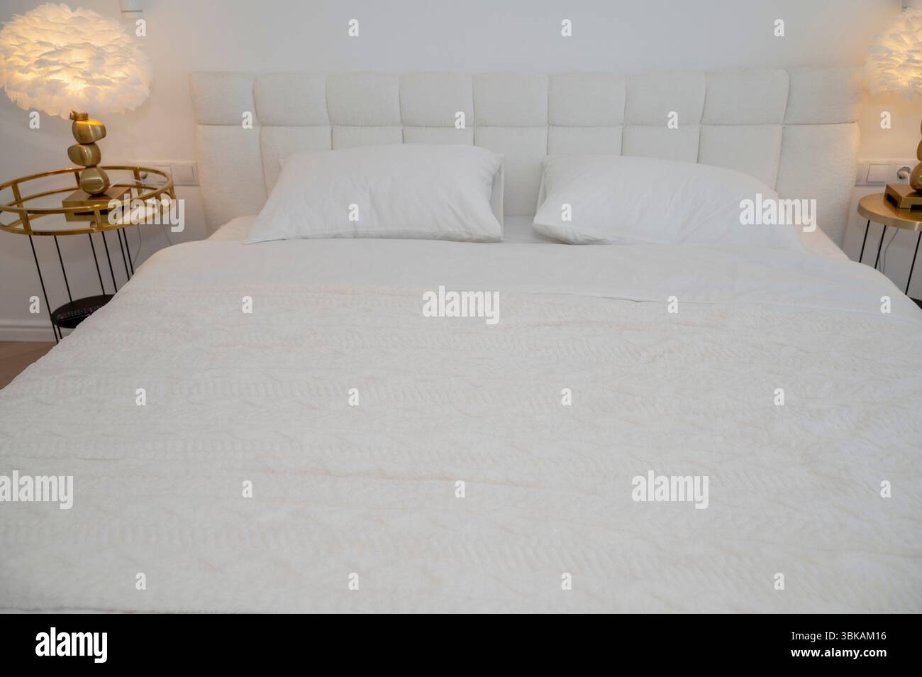 Ein gemütliches, modernes Hotelzimmer mit einem ordentlich gefertigten weißen Bett. Das Zimmer ist in minimalistischem Stil eingerichtet Stockfoto