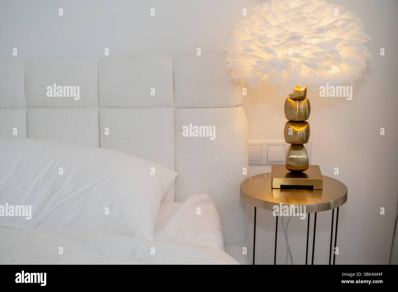 Inneneinrichtung des Schlafzimmers mit moderner Leselampe auf dem Tisch neben dem Doppelbett mit Kissen. Stockfoto