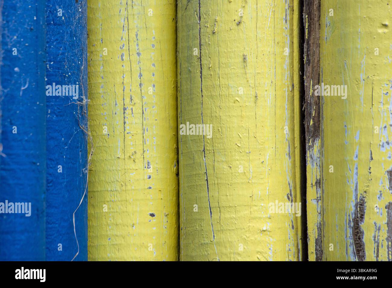 Gelb und blau lackierte Holzhölzer einer alten Holzhütte Stockfoto