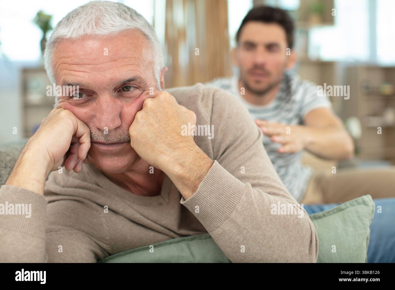 Vater, der seinen Sohn verpönt, saß auf einer Couch Stockfoto