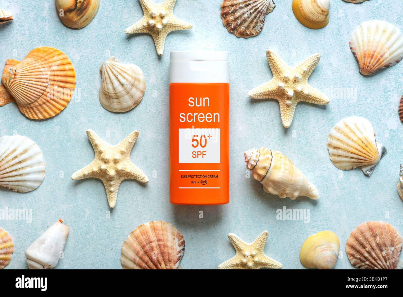 Blick von oben auf eine Flasche Sonnencreme mit 50+ Aufschriften und Sternenfische über blauem Hintergrund. Konzept des Sonnenschutzes Stockfoto