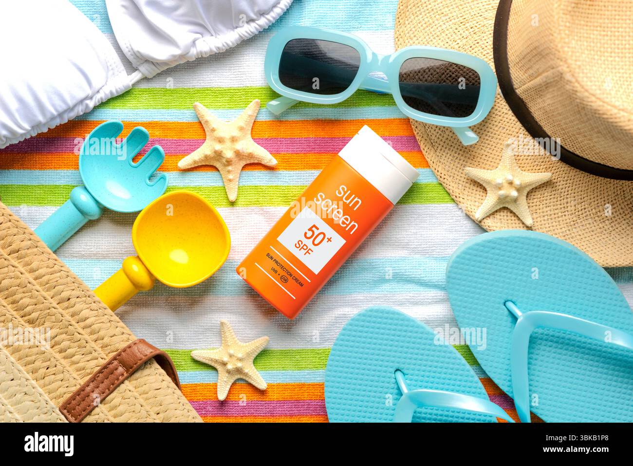 Blick von oben auf eine Flasche Sonnencreme mit 50+ Aufschriften, Sonnenbrillen und Strandartikel auf einem Strandtuch. Konzept des Sonnenschutzes Stockfoto