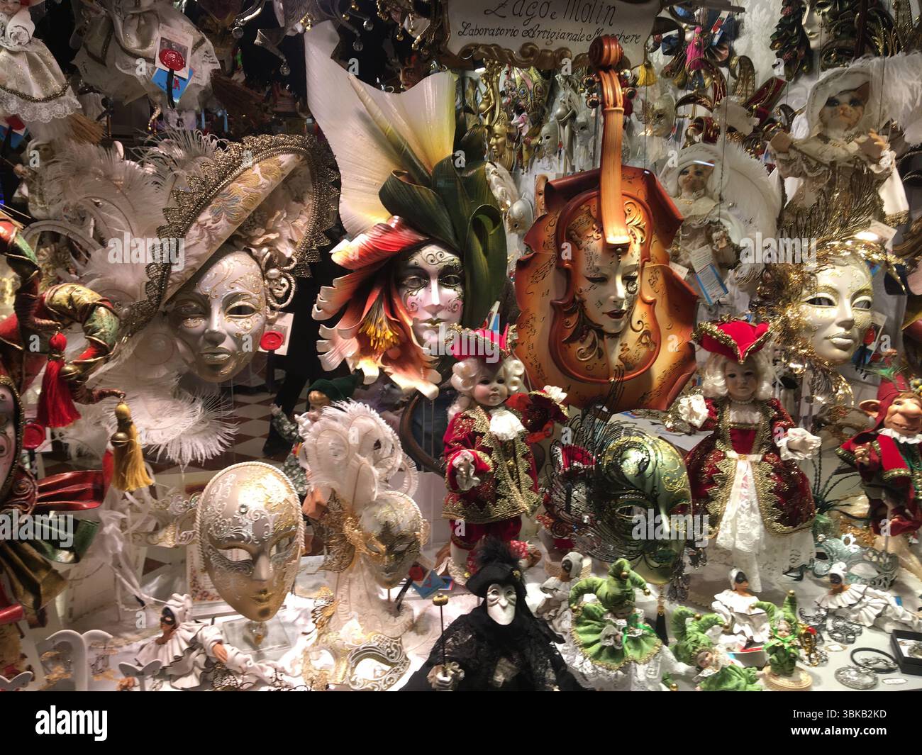 Farbenfrohe venezianische Masken schmücken ein Schaufenster in Venedig und spiegeln Karnevalstradition, handwerkliche Handwerkskunst und festlichen Charme wider. Stockfoto