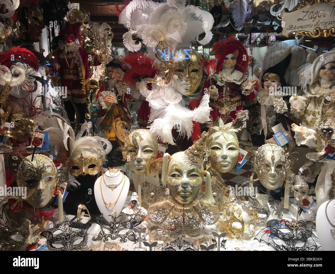 Farbenfrohe venezianische Masken schmücken ein Schaufenster in Venedig und spiegeln Karnevalstradition, handwerkliche Handwerkskunst und festlichen Charme wider. Stockfoto