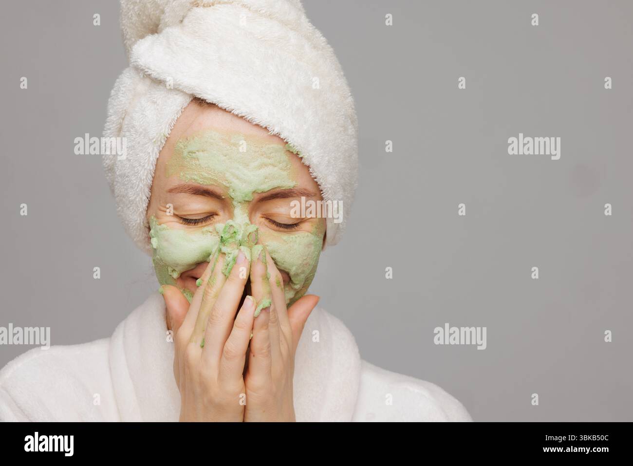 Fröhliche Frau mit grünem Sauerstoffschaum Gesichtsmaske lacht und genießt ein spielerisches Hautpflege- und Schönheitsritual zu Hause. Stockfoto