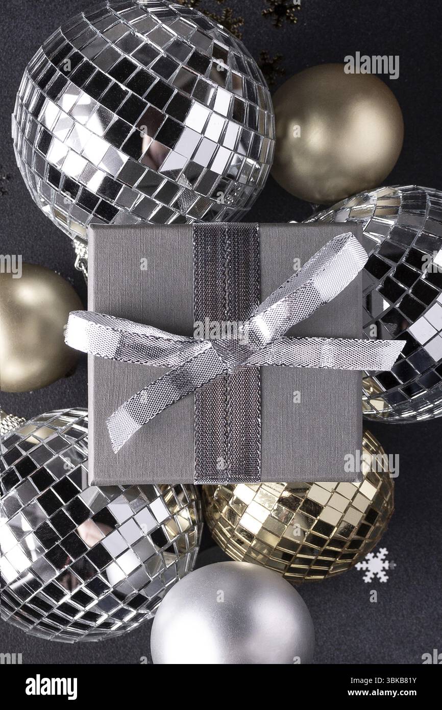 Weihnachtskugeln in Gold und Silber, Geschenkbox auf schwarzem Hintergrund. Weihnachtsdekoration Stockfoto