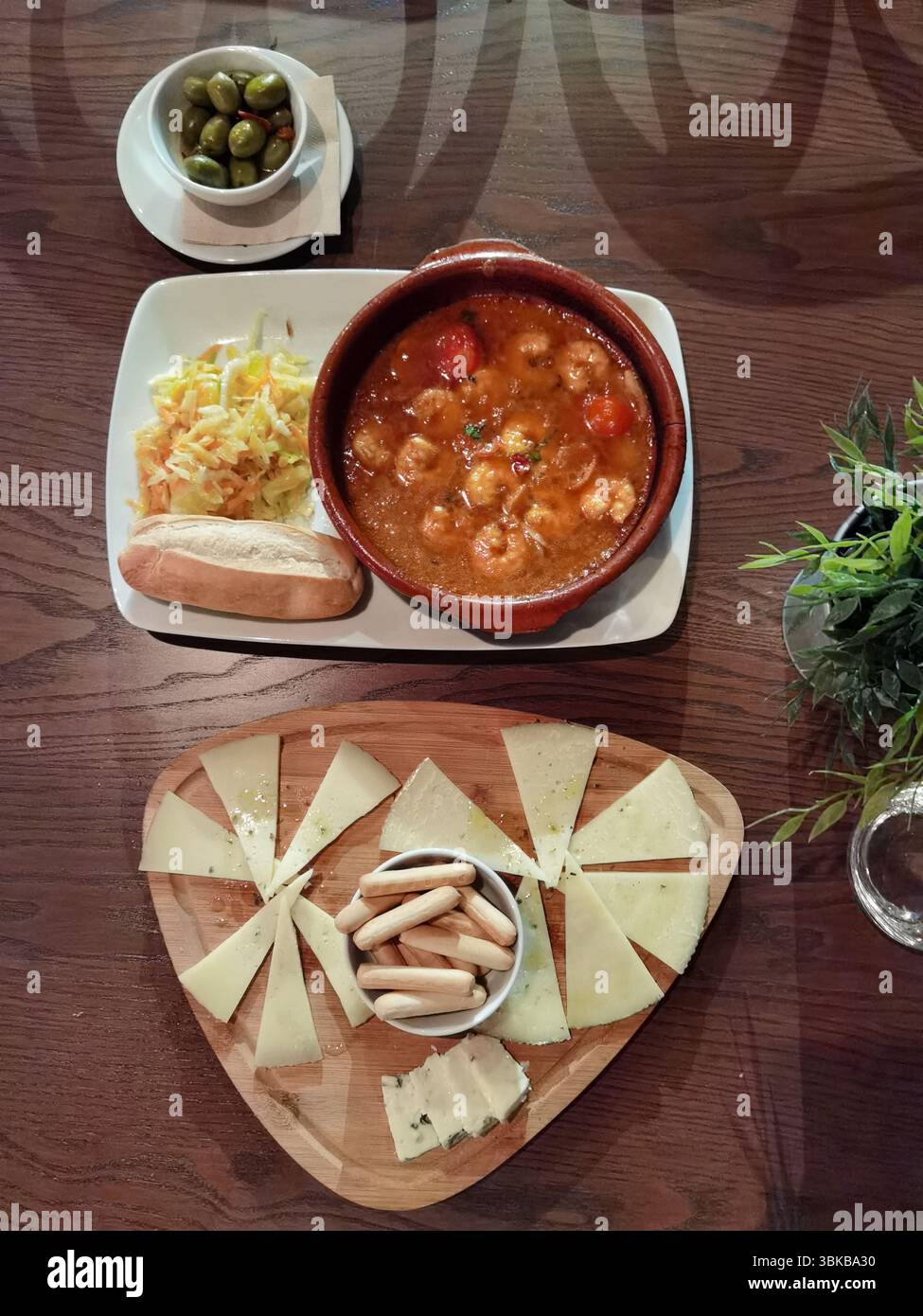 Käsewürfel, Knoblauchgarnelen, grüne Oliven. Traditionelle spanische Tapas, serviert auf einem rustikalen Tisch, mit lebhaften mediterranen Aromen, perfekt für Fo Stockfoto