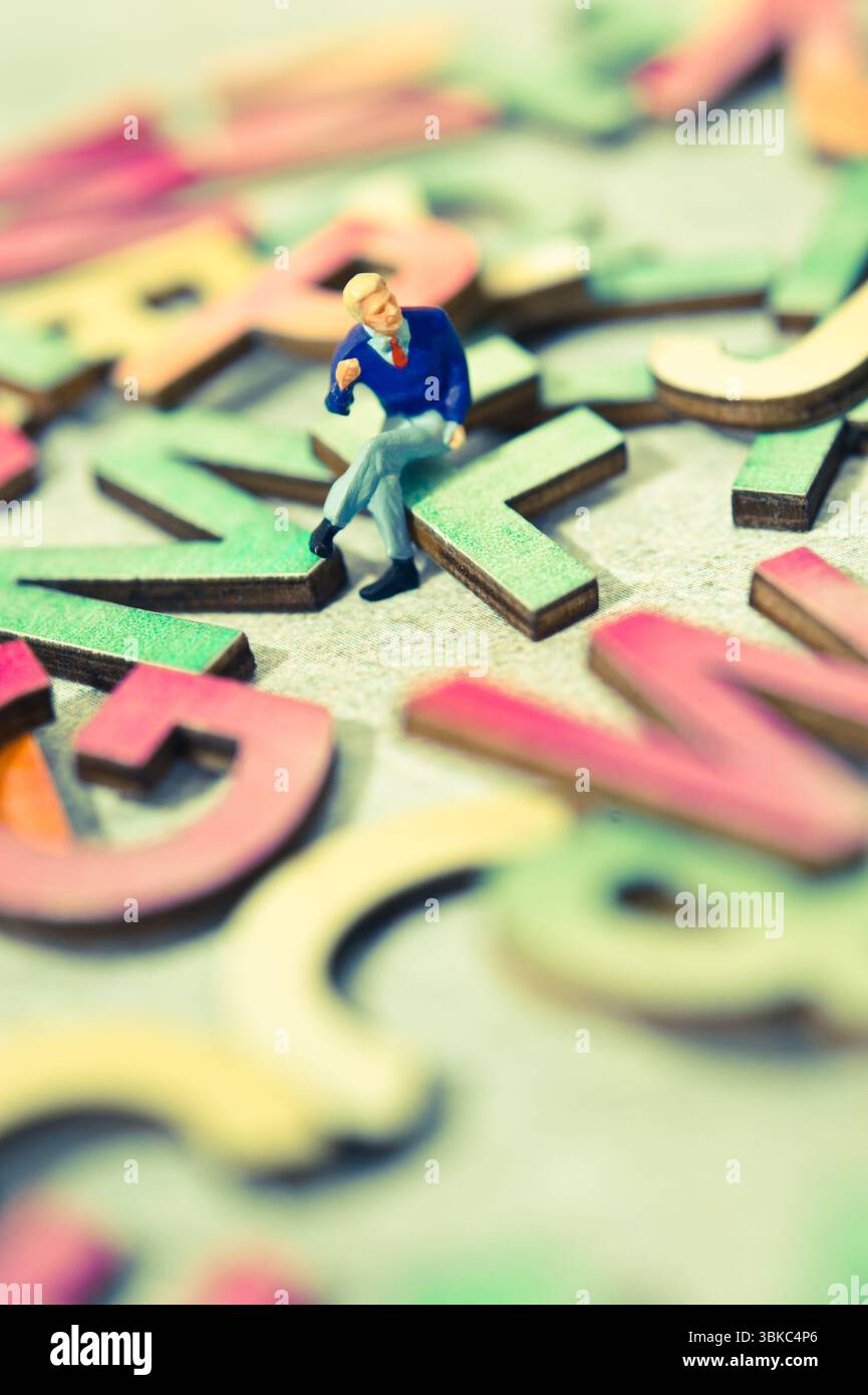 Miniaturfigur auf Alphabetbuchstaben, Sprachlehre Stockfoto