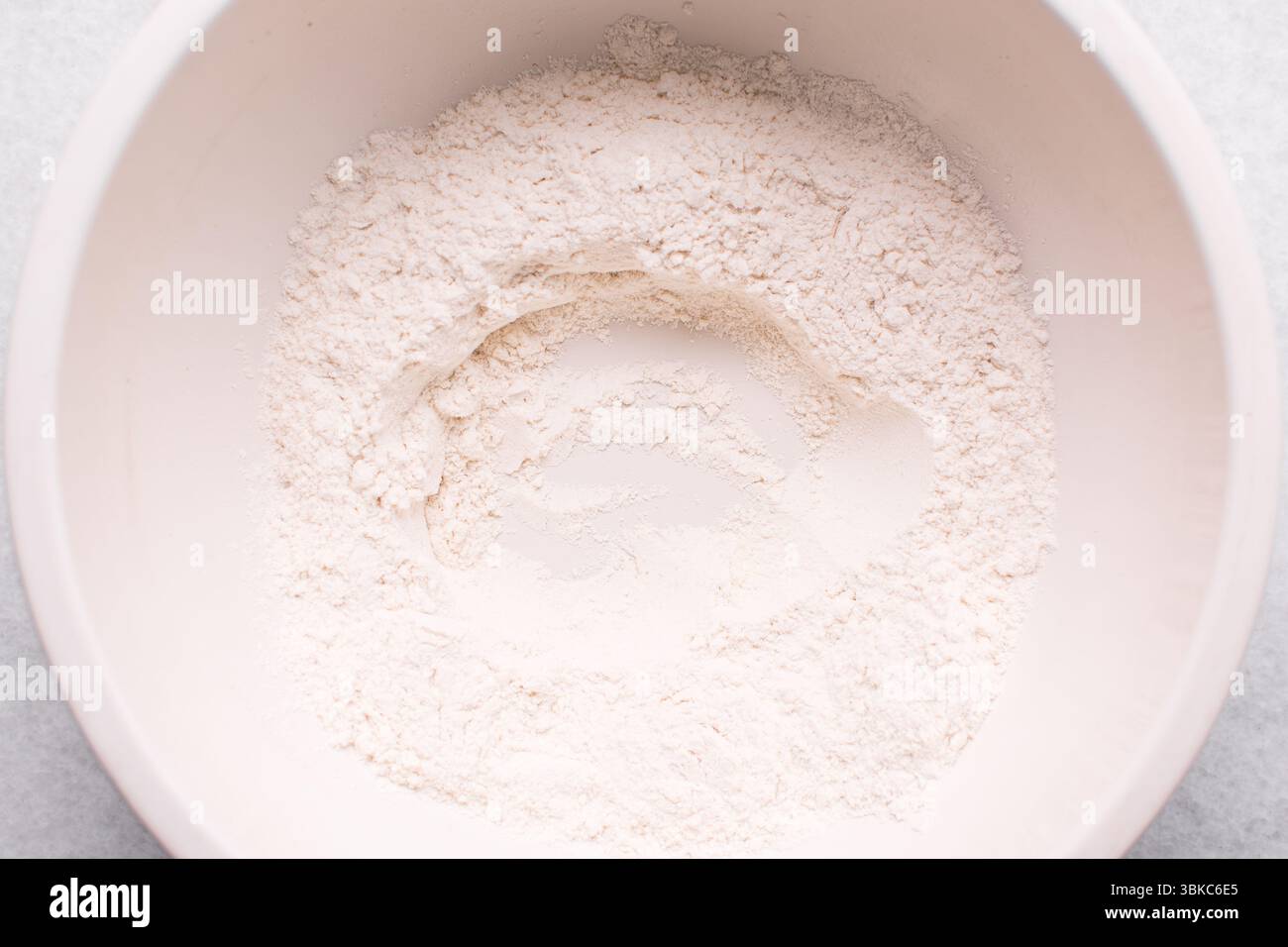 Draufsicht auf Allzweckmehl in einer Schüssel, Draufsicht auf Backmehl auf einer weißen Arbeitsplatte Stockfoto