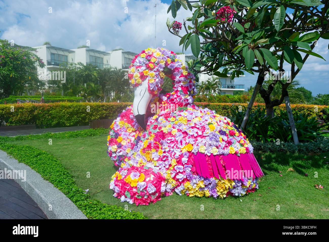 Tierkunst eines flamengos mit Blumen in der Nähe von Kuta Beach, Denpasar, Bali, Indonesien Stockfoto