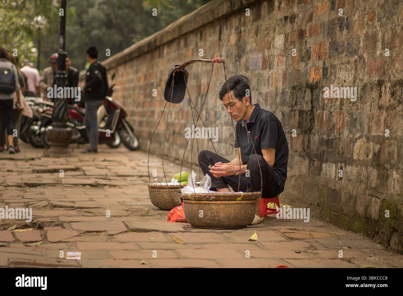Mann sitzt auf der Straße, Hanoi Stockfoto