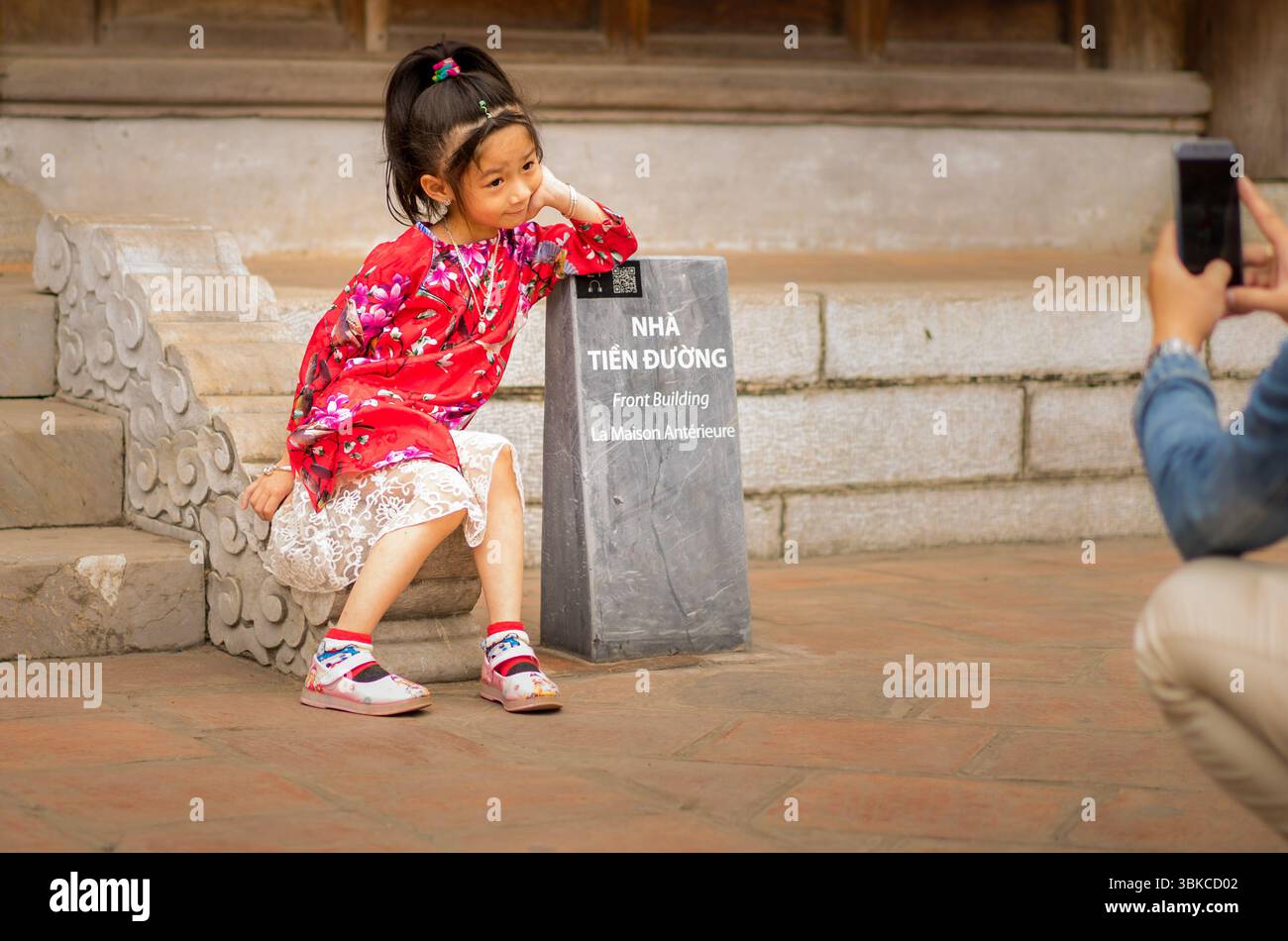 Ein lokales Kind in rotem Kleid hat ein Foto im Literaturtempel in Hanoi gemacht Stockfoto