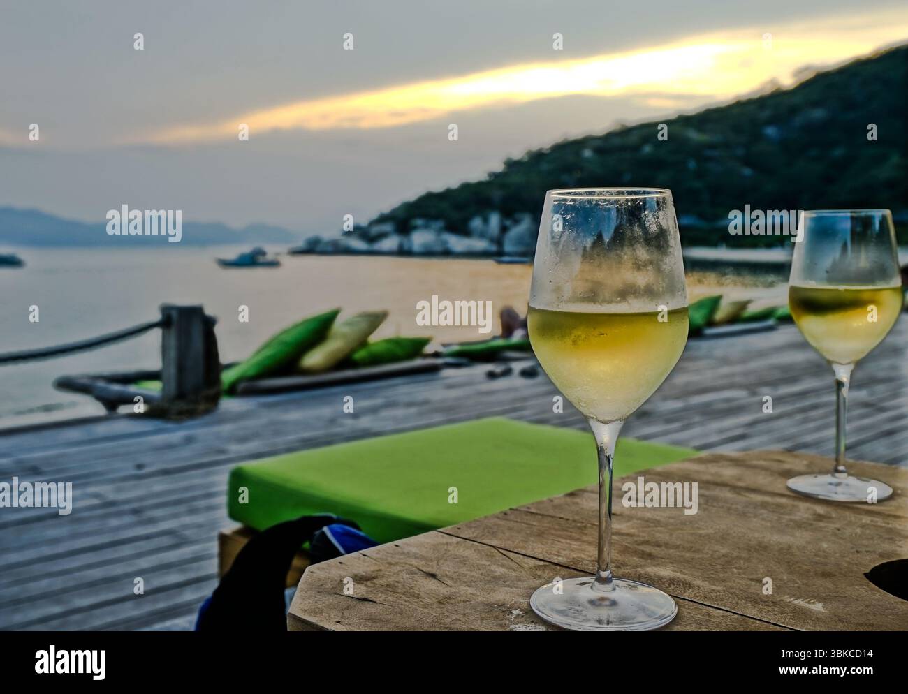 Zwei Gläser Weißwein auf einem Tisch neben der abendlichen Strandszene Stockfoto