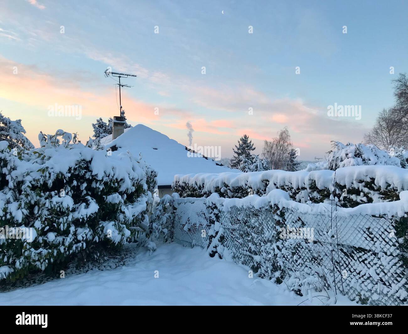 Schneebedeckter Garten und Dach bei Sonnenaufgang, Frankreich Stockfoto