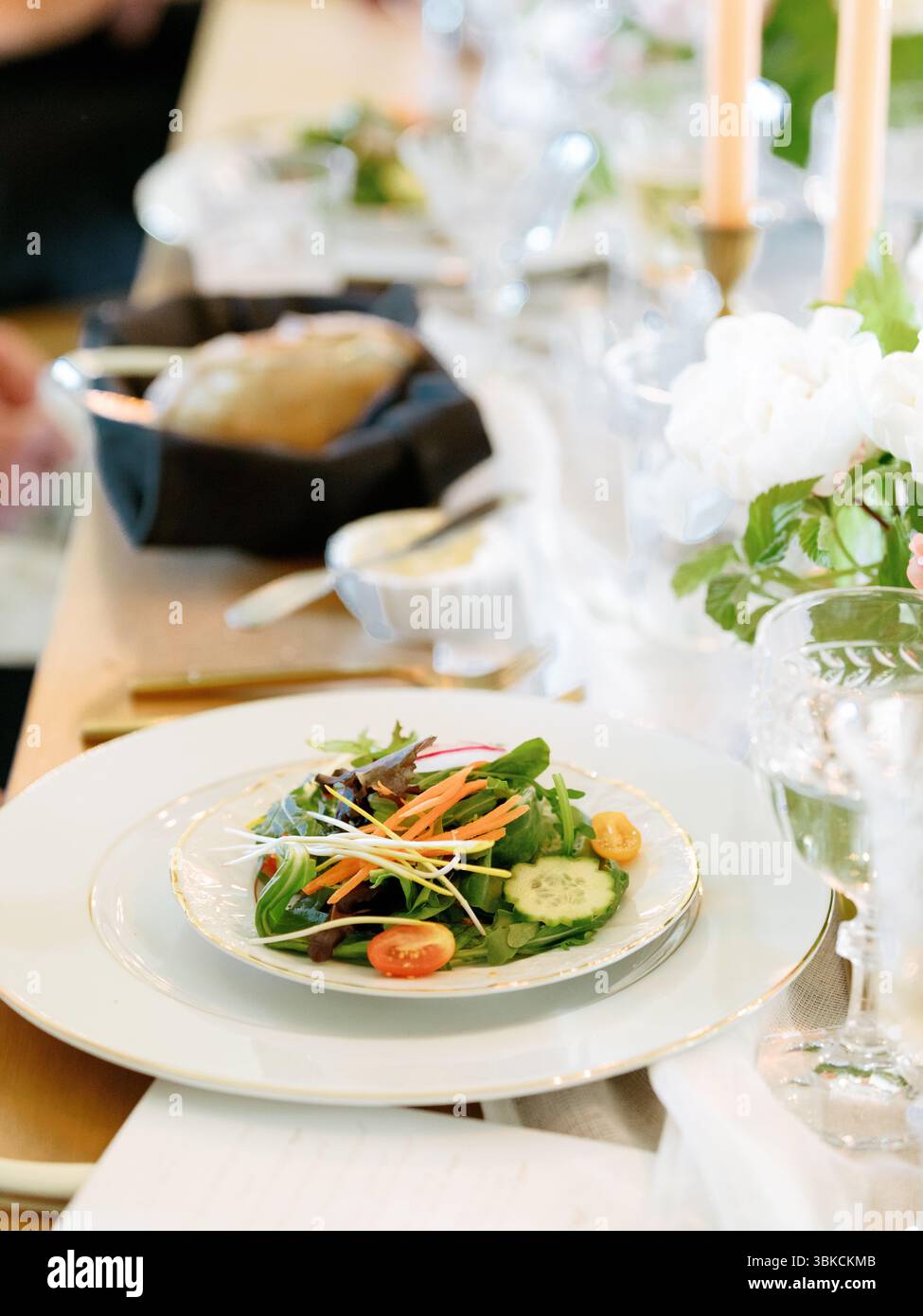 Eleganter Salat auf einem formellen Tisch mit Blumen Stockfoto