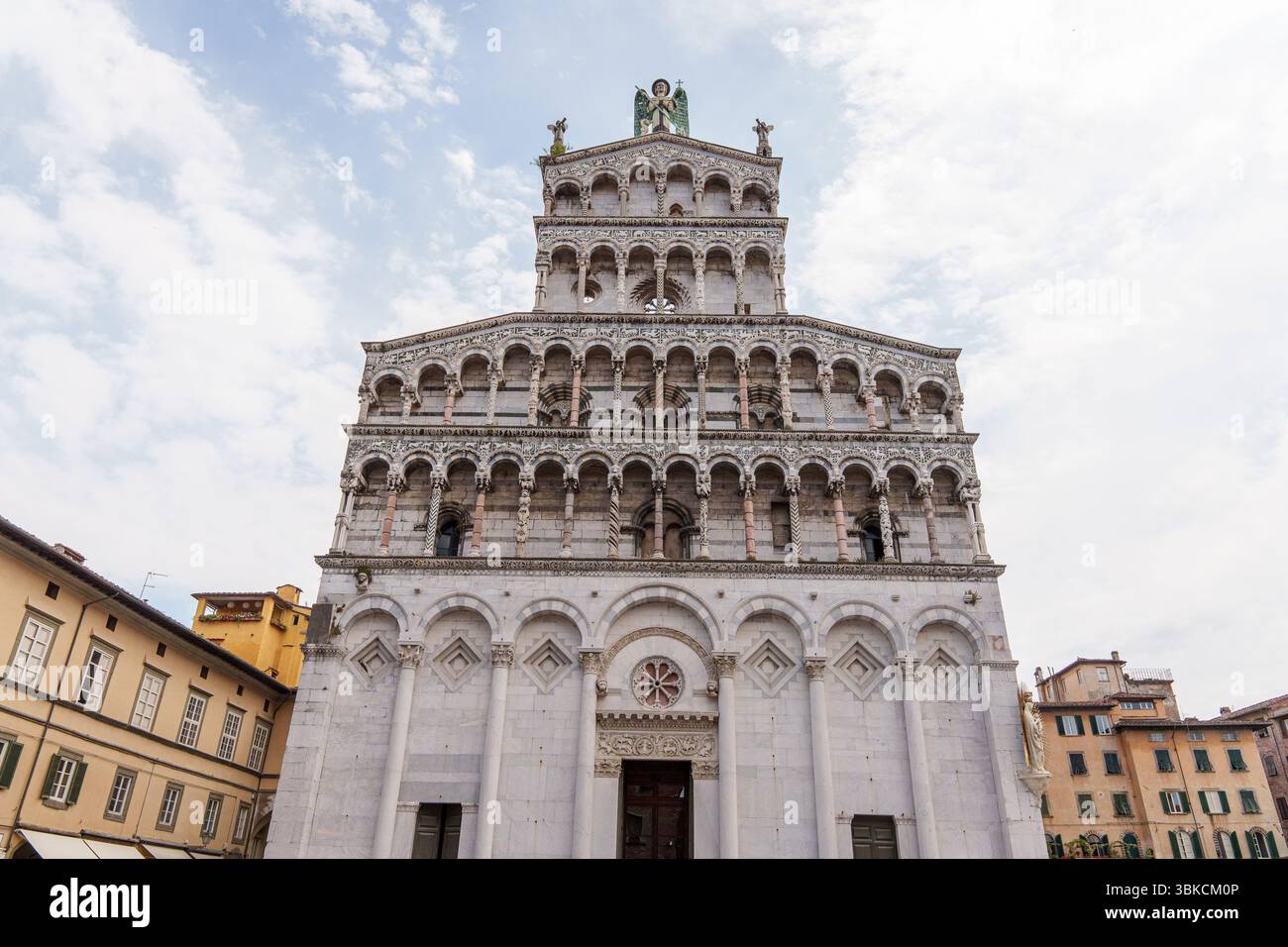 Fassade von San Michele in der Kirche Foro in Lucca, Italien, mit kunstvollen Bögen und Statuen unter bewölktem Himmel. Hochwertige Fotos Stockfoto