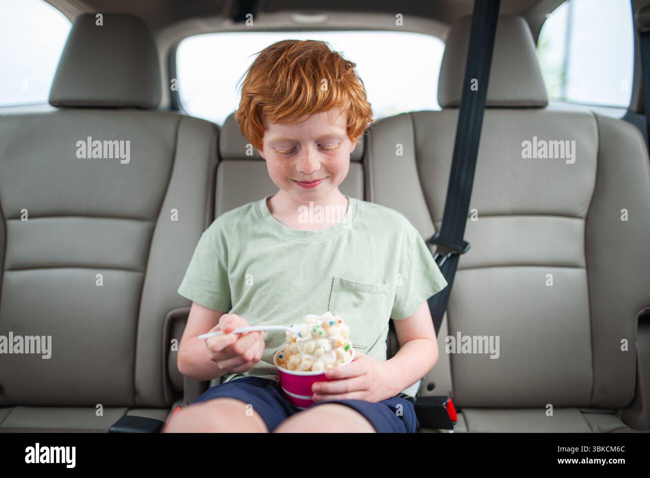 Glückliches Kind mit Eisbecher im Fahrzeug Stockfoto