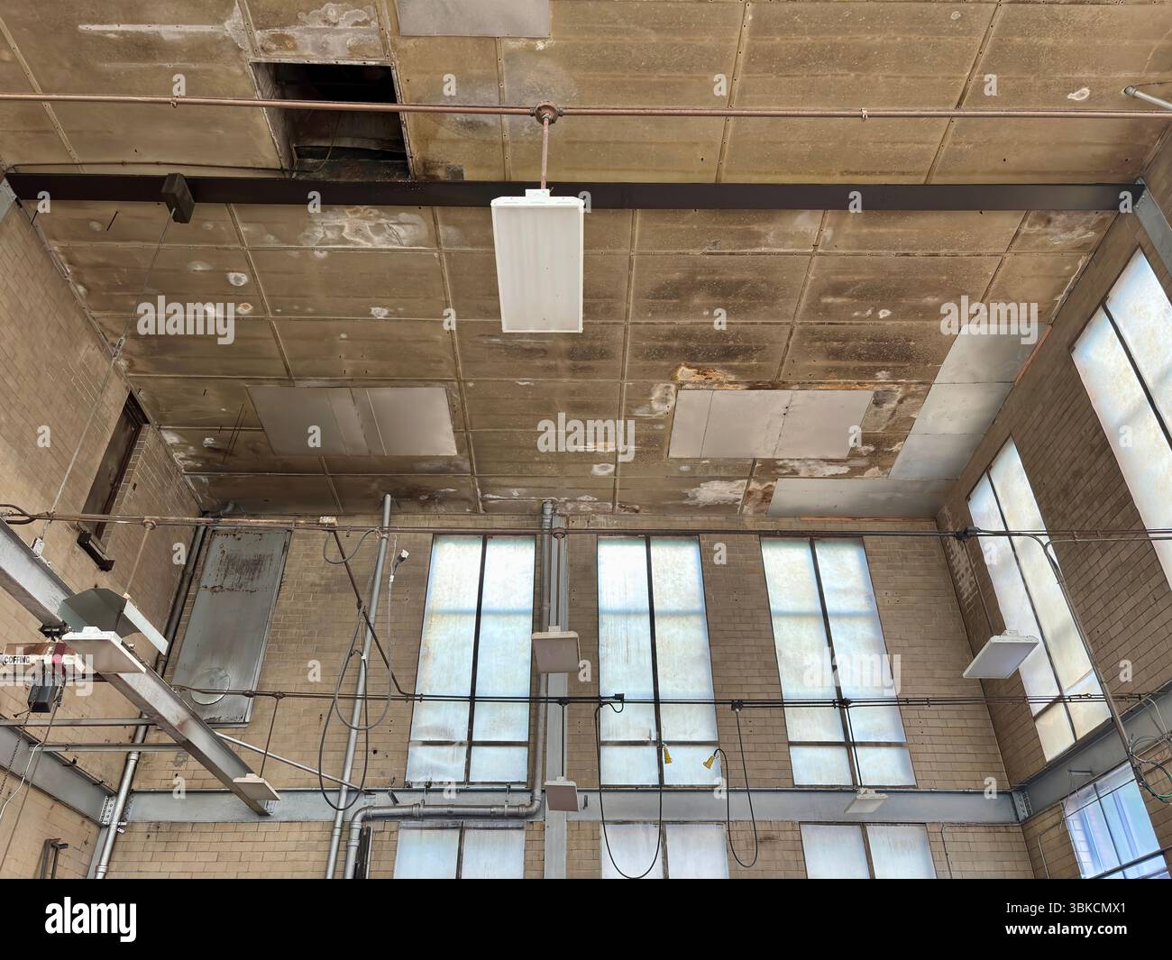 Hohe Fenster, Deckenleuchten, schmutzige Decke in einer alten Fabrik Stockfoto
