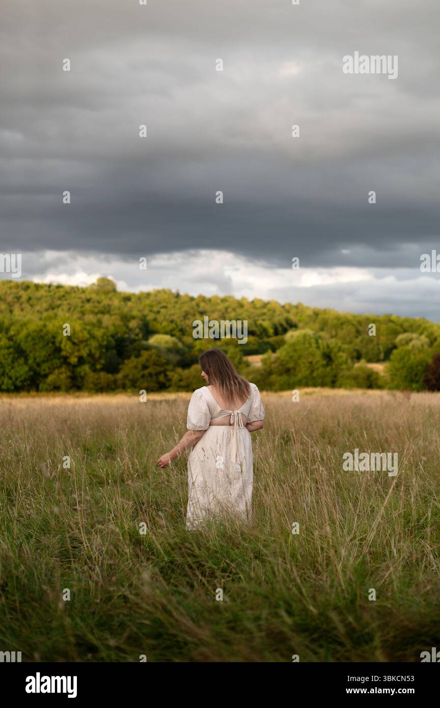 Frau, die vor dem Sturm im hohen Gras stand. Rückansicht. Stockfoto