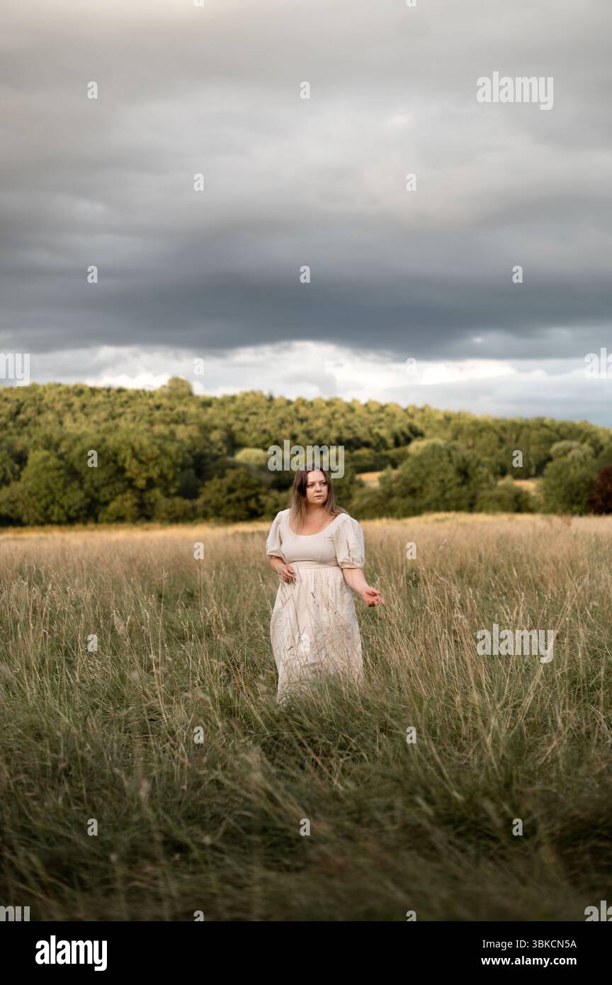 Frau, die vor dem Sturm in hohem Gras läuft Stockfoto