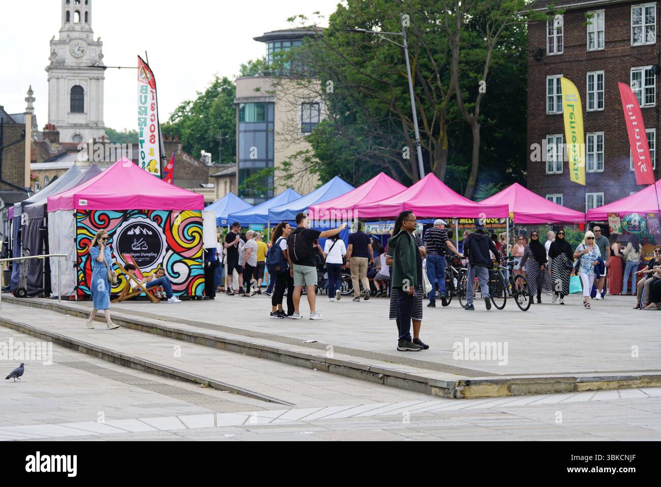Lebhafte Marktszene im Freien mit farbenfrohen Verkaufsständen und Menschenmengen. Greenwich, London, England Stockfoto