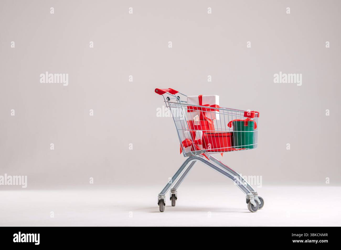Warenkorb voller Geschenkkartons auf hellem Hintergrund. Stockfoto