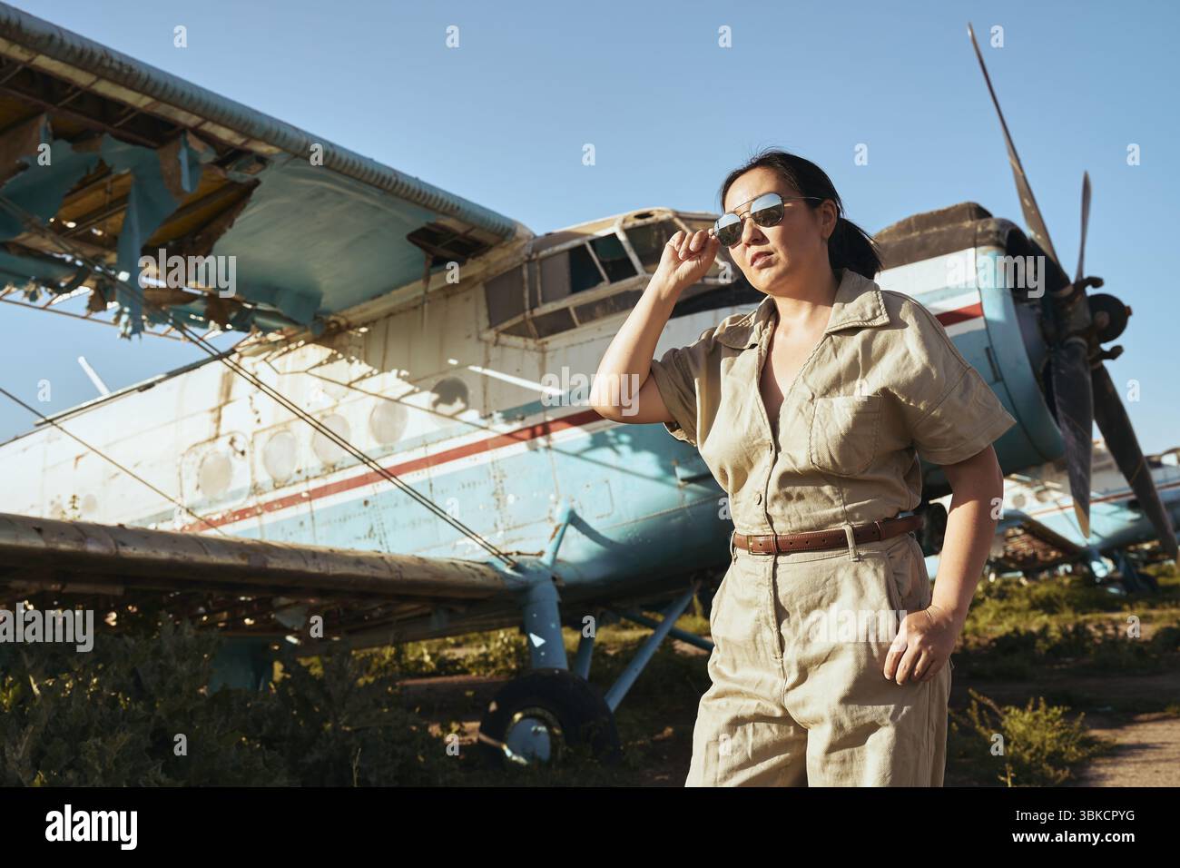 Frau in Fliegerausrüstung im Flugzeug, sonniger Tag Stockfoto