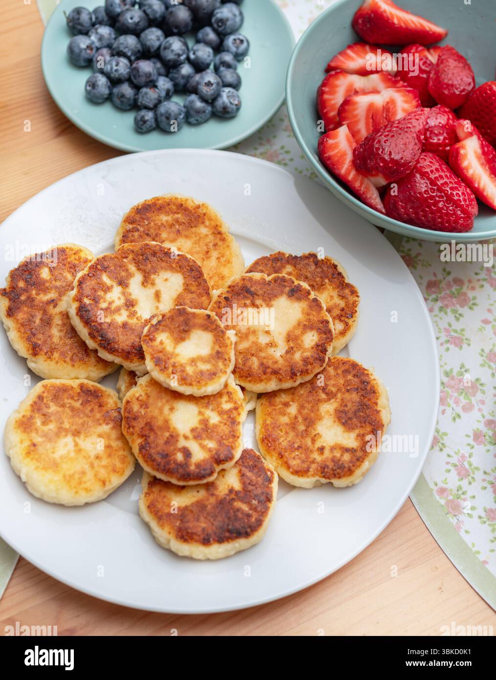 Syrniki oder gebratene Hüttenkäsepfannkuchen auf weißem Teller auf dem Tisch. Stockfoto