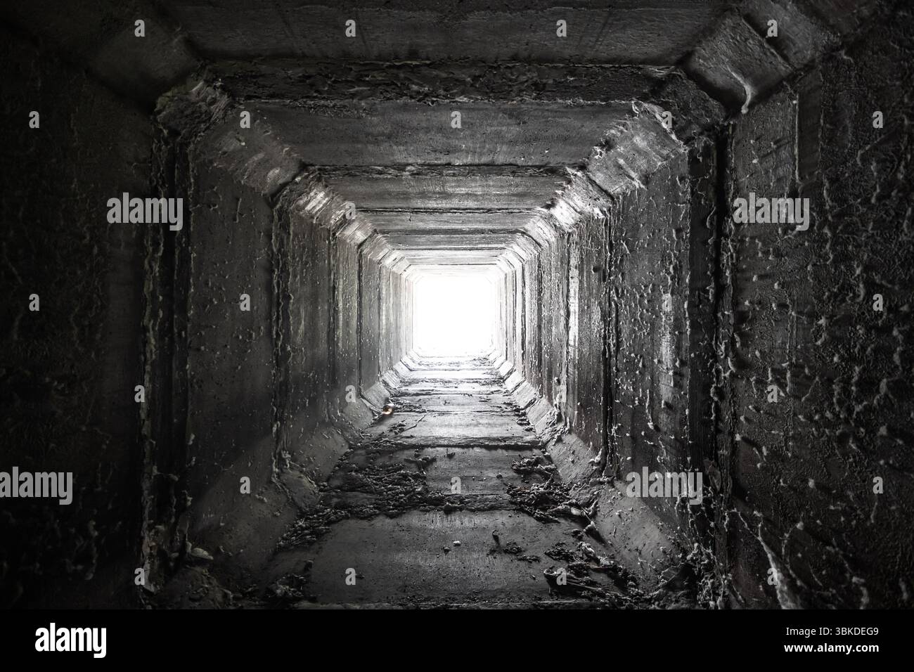 Leerer quadratischer Betontunnel mit Licht am Ende Getrockneter Düker. Stockfoto