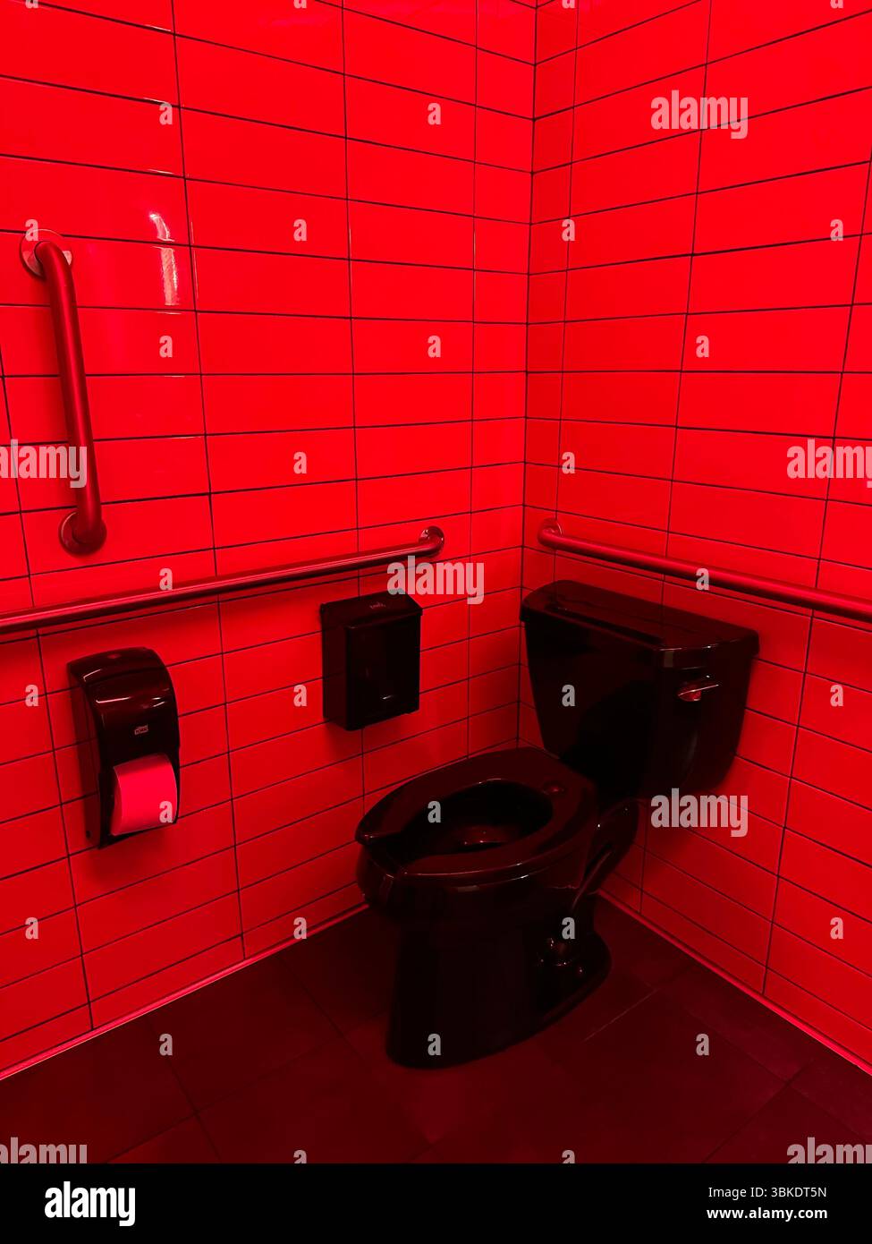 Ein rotes Badezimmer mit einer schwarzen Toilette. Stockfoto