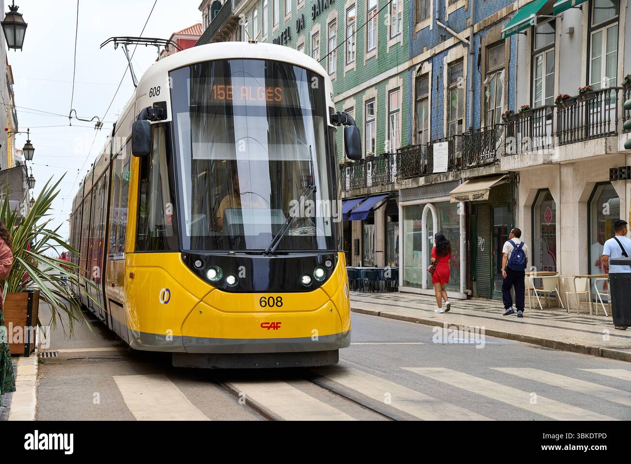 Lissabon, Portugal - 10. Juni 2025: Eine moderne gelbe Straßenbahn der Linie 15E fährt durch die Altstadt von Lissabon und passiert die engen Gassen mit den traditionellen Häuserfassaden *** eine moderne gelbe Straßenbahn der Linie 15E fährt durch die Altstadt von Lissabon und passieren die engen Gassen mit den traditionellen Häuserfassaden Stockfoto
