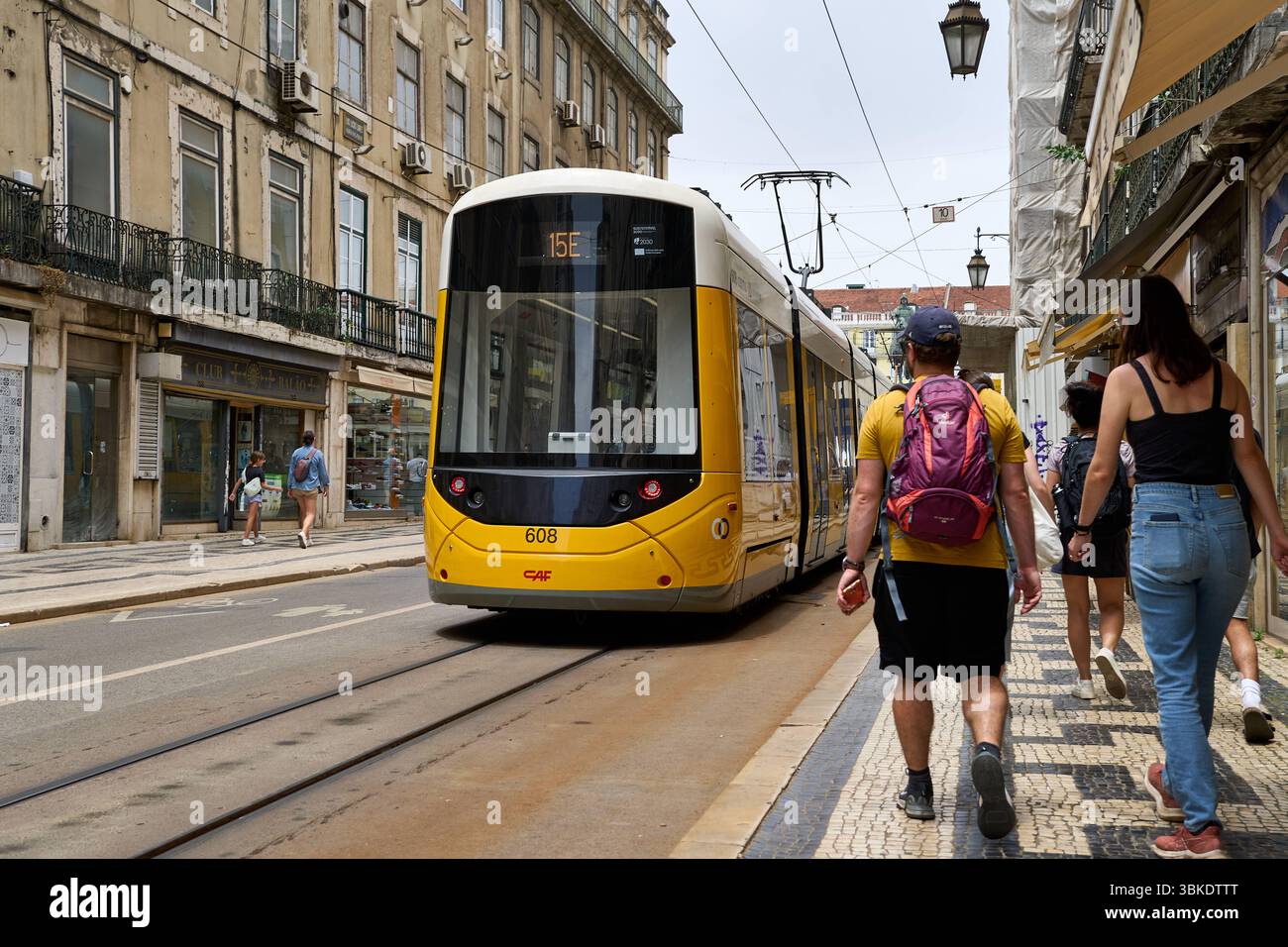 Lissabon, Portugal - 10. Juni 2025: Eine moderne gelbe Straßenbahn der Linie 15E fährt durch die Altstadt von Lissabon und passiert die engen Gassen mit den traditionellen Häuserfassaden *** eine moderne gelbe Straßenbahn der Linie 15E fährt durch die Altstadt von Lissabon und passieren die engen Gassen mit den traditionellen Häuserfassaden Stockfoto
