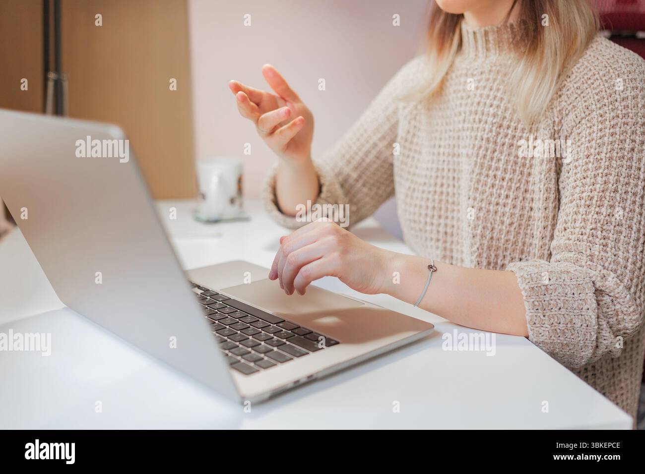 Die Frau bewegt sich mit der Hand, während sie von zu Hause aus mit einem Laptop arbeitet. Nahaufnahme von weiblichen Händen und Laptop, Frau erklärt während Video c Stockfoto